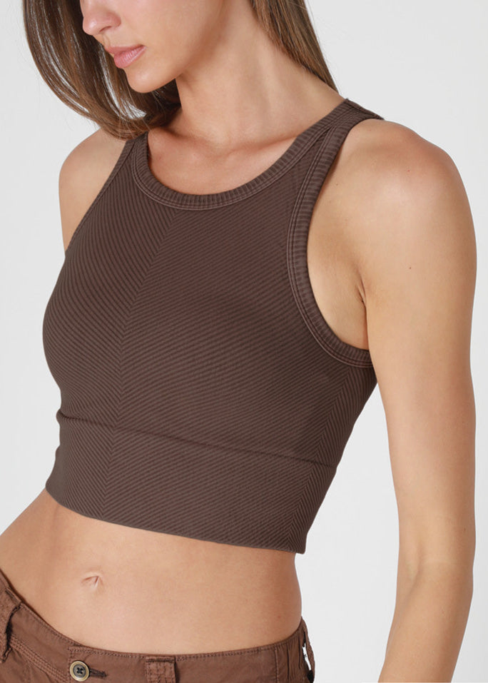 Woman wearing a brown sleeveless top and pants on a white background