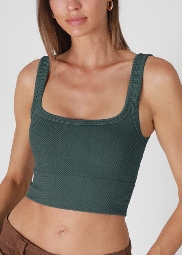 Woman wearing a green textured tank top against a plain background