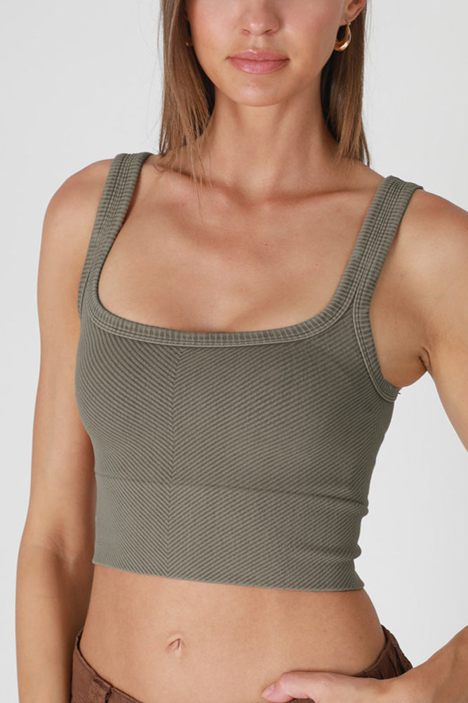 Woman wearing a textured green crop top on a plain background
