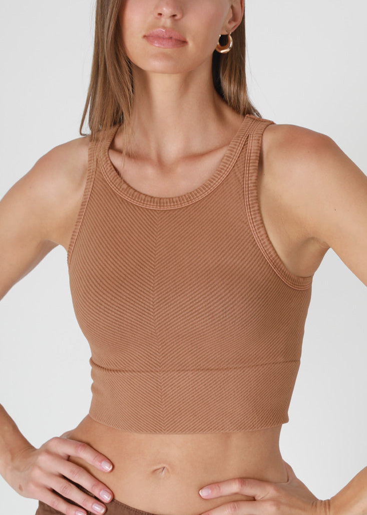 Woman wearing a brown knit tank top against a white background